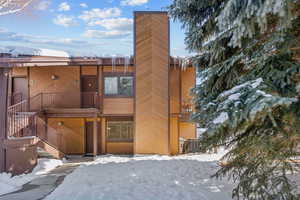 Snow covered back of property with stairs