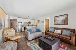 Living area with dark wood-style floors, recessed lighting, and baseboards