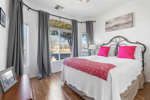 Bedroom with a ceiling fan, visible vents, dark wood finished floors, and baseboards