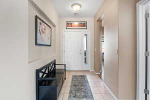 Foyer with light tile patterned flooring, visible vents, baseboards, and a textured ceiling