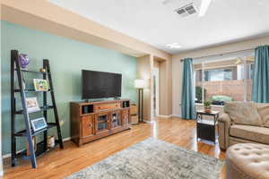 Living room with baseboards, visible vents, and wood finished floors