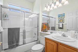 Bathroom with enclosed tub / shower combo, vanity, and toilet