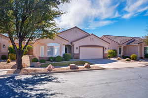 Mediterranean / spanish home with a tile roof, driveway, an attached garage, and stucco siding