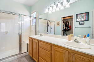 Bathroom with a stall shower, a walk in closet, and a sink