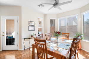 Dining space with light wood-type flooring, visible vents, ceiling fan, and baseboards