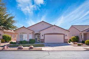 Mediterranean / spanish-style home featuring a garage, driveway, a tiled roof, and stucco siding