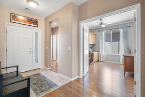 Entryway featuring light wood-type flooring, visible vents, crown molding, and baseboards