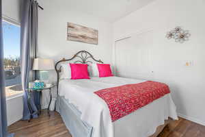 Bedroom with dark wood-type flooring, a closet, and baseboards