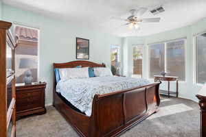 Bedroom featuring light carpet, baseboards, visible vents, and a ceiling fan