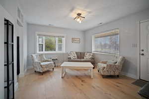 Sitting room with light wood-type flooring, visible vents, and baseboards