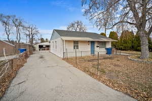 View of front of property featuring a fenced front yard, an outdoor structure, and a shingled roof