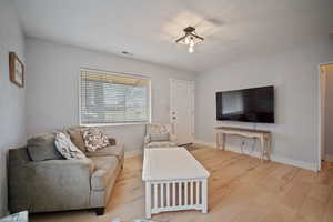 Living area featuring visible vents, baseboards, and wood finished floors