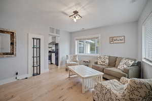 Living room featuring baseboards, visible vents, and light wood finished floors