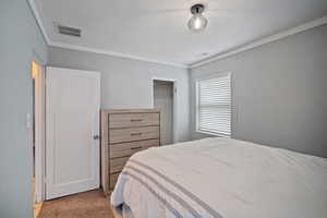 Bedroom featuring light carpet, crown molding, visible vents, and a closet