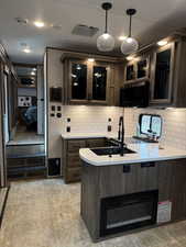 Kitchen with light countertops, tasteful backsplash, a sink, and glass insert cabinets