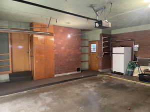 Garage featuring a garage door opener and white fridge