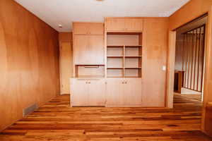 Interior space featuring visible vents, wood walls, and light wood finished floors