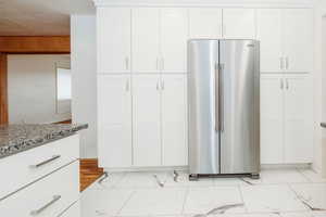 Kitchen with high quality fridge, light stone countertops, and white cabinets