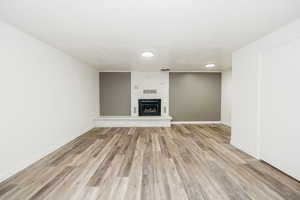 Unfurnished living room with crown molding, a large fireplace, and light wood-type flooring