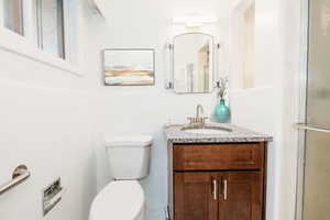 Bathroom with vanity, toilet, a shower with door, and tile walls