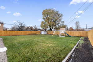 View of yard with a shed, an outbuilding, a playground, and a fenced backyard