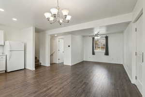 Unfurnished dining area featuring stairs, recessed lighting, dark wood-type flooring, baseboards, and ceiling fan with notable chandelier