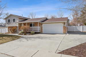 Tri-level home with an attached garage, covered porch, concrete driveway, and brick siding