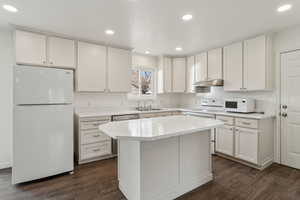 Kitchen featuring light countertops, white appliances, white cabinets, and under cabinet range hood