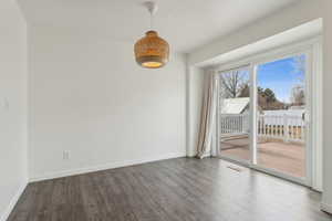 Spare room featuring wood finished floors, visible vents, and baseboards