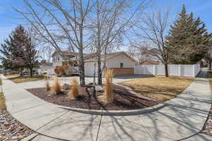 View of front of home featuring driveway, brick siding, fence, and a residential view