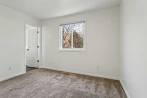 Spare room with carpet, visible vents, and baseboards