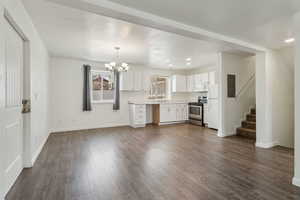 Kitchen with white appliances, white cabinets, dark wood-style floors, decorative light fixtures, and light countertops