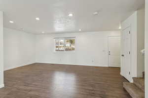 Spare room featuring baseboards, dark wood finished floors, a textured ceiling, and recessed lighting