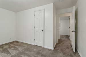 Interior space featuring a textured ceiling, carpet, and baseboards