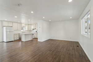 Unfurnished living room with baseboards, dark wood finished floors, and recessed lighting