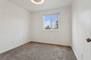 Spare room with carpet, visible vents, and baseboards