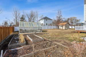 View of yard featuring an outbuilding, an exterior structure, a fenced backyard, and a shed