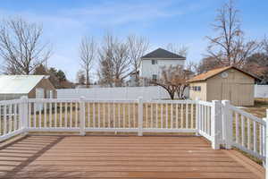 Wooden terrace featuring an outbuilding, a fenced backyard, and a shed