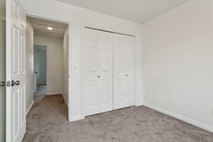 Unfurnished bedroom featuring light carpet, baseboards, and a closet