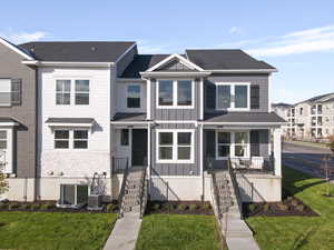 Multi unit property with board and batten siding, a front yard, a shingled roof, and central air condition unit