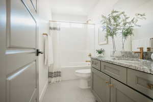 Bathroom featuring baseboards, toilet, tile patterned floors, shower / bath combo with shower curtain, and vanity