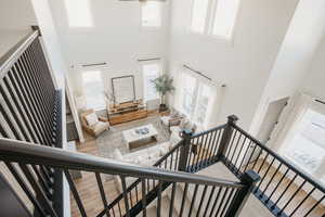 Stairway with a wealth of natural light, a towering ceiling, and wood finished floors