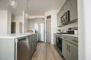 Kitchen with hanging light fixtures, appliances with stainless steel finishes, light countertops, and a sink