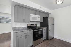 Kitchen featuring stainless steel appliances, gray cabinets, and light stone countertops