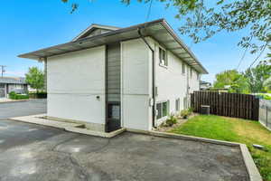 View of property exterior featuring brick siding, fence, central AC, and a yard