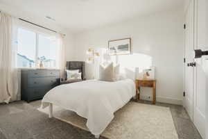 Bedroom with baseboards, visible vents, and light colored carpet