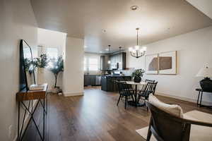 Dining area with dark wood-type flooring, recessed lighting, a chandelier, and baseboards