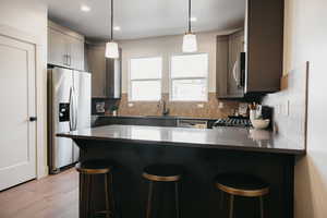 Kitchen featuring stainless steel appliances, decorative light fixtures, and a kitchen bar