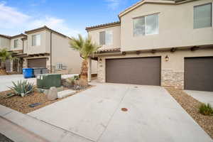 View of front of house featuring stone siding, an attached garage, concrete driveway, and stucco siding