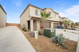 Mediterranean / spanish-style home with driveway, a garage, stone siding, fence, and stucco siding